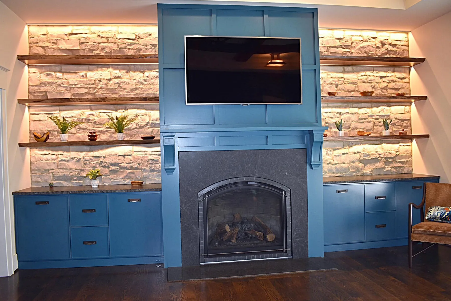 Blue painted hearth surround with a television above and lit stone shelving