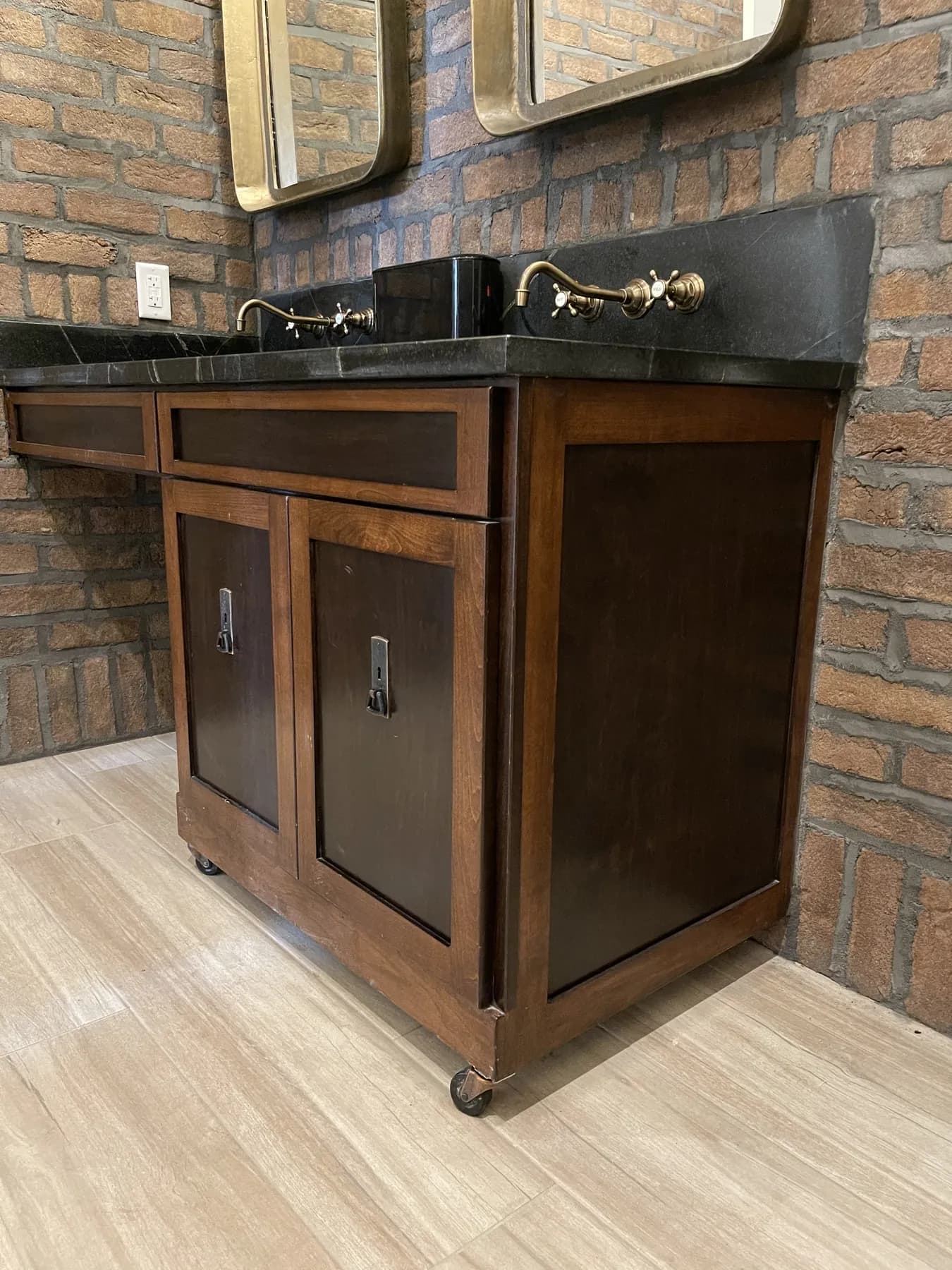 Stained rolling cabinet beside the black stone vanity