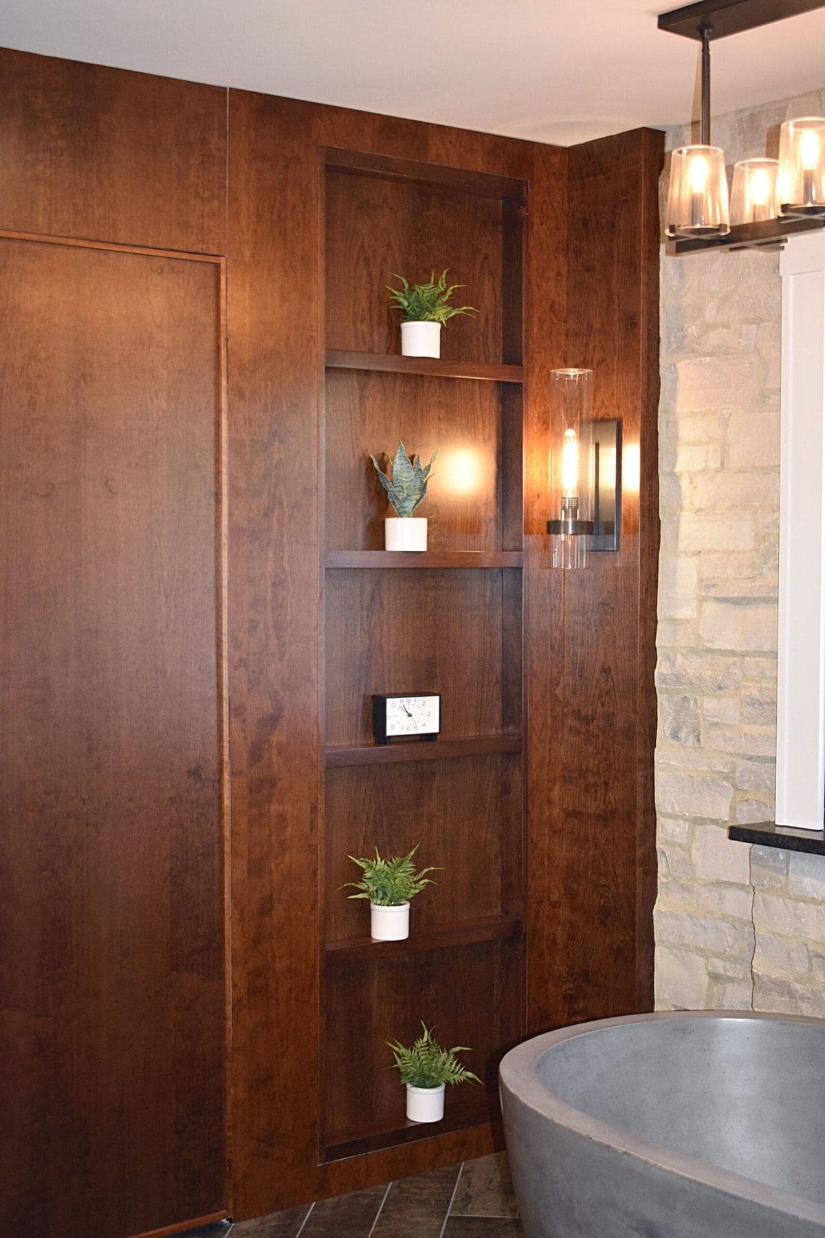 Stained wood panelling with a niche of open shelves beside a concrete soaking tub