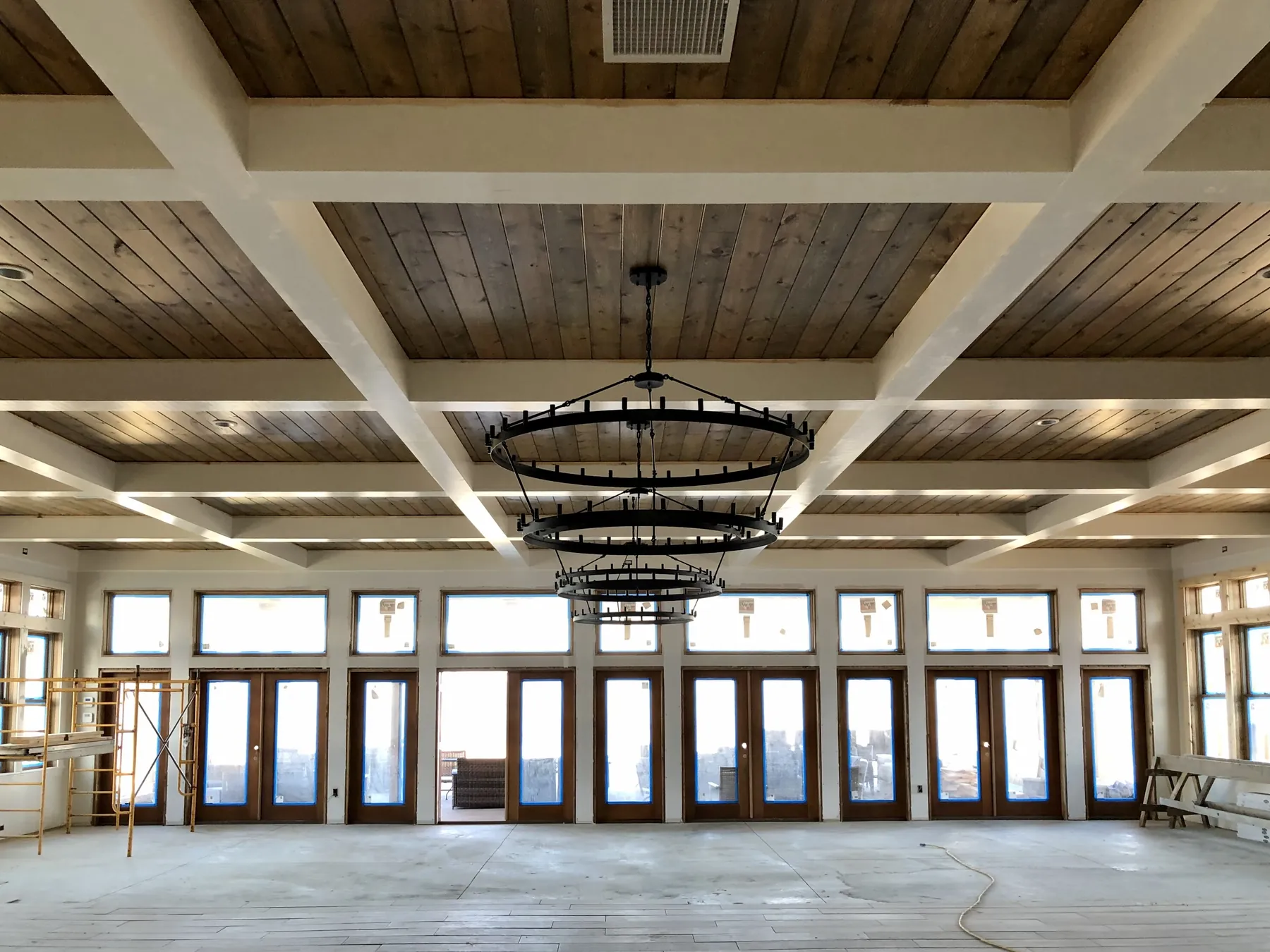 Coffered plank ceiling with iron chandeliers over the window wall