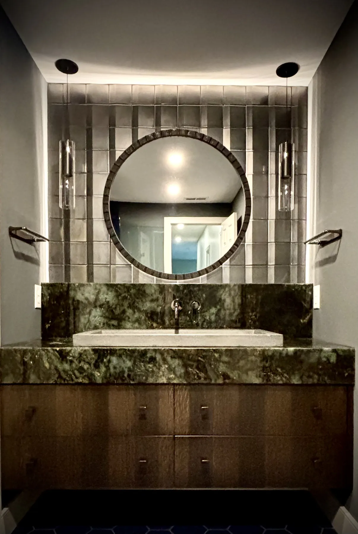 Green marble tub surround with a round mirror and mirrored tile