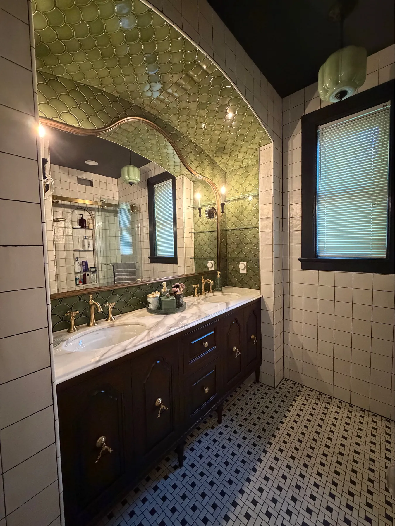 Green tiled bath with a stained vanity and marble top beside the window