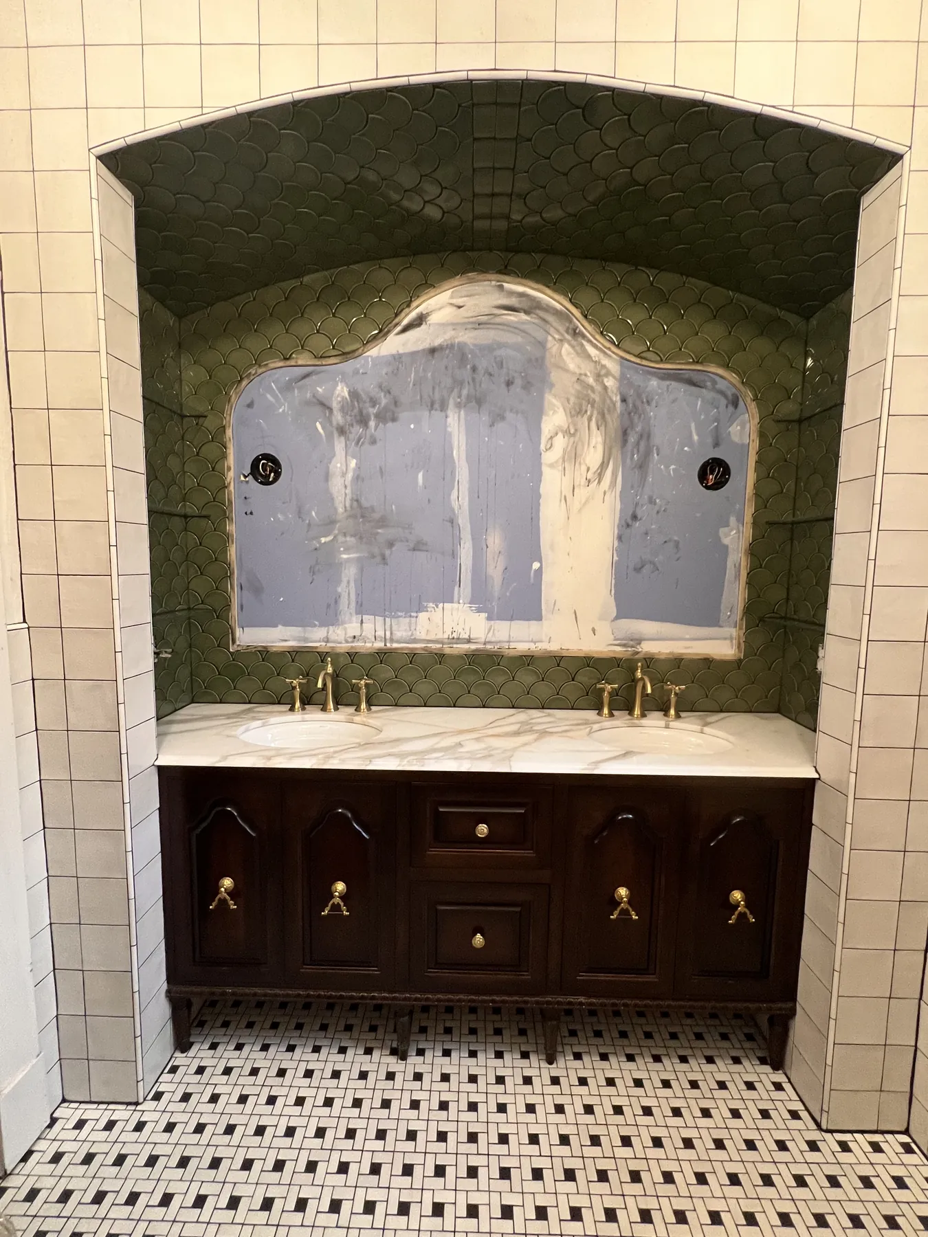 Stained vanity with brass pulls beneath a marble splash and green tile