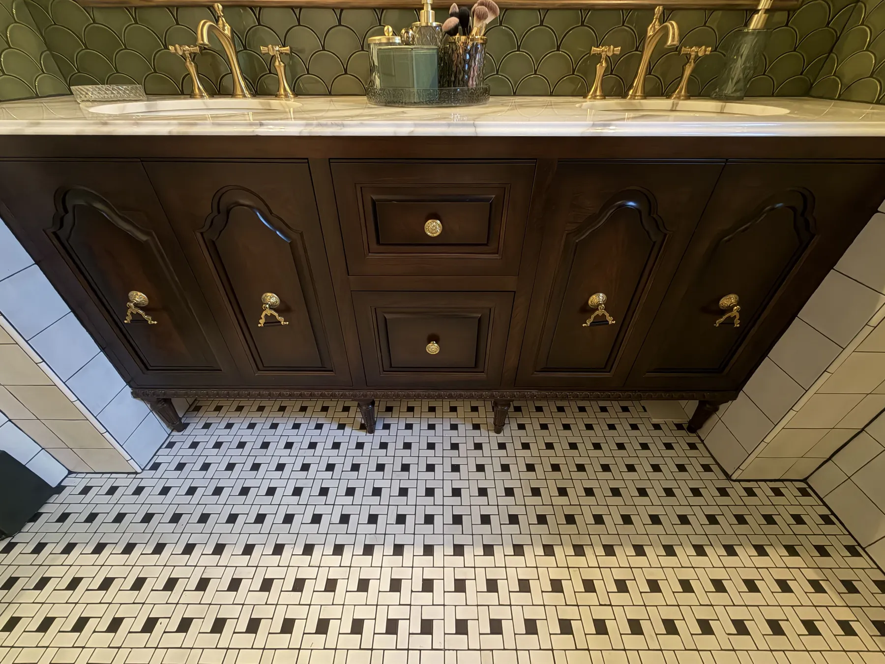 Stained vanity with brass faucets above a basketweave tile floor