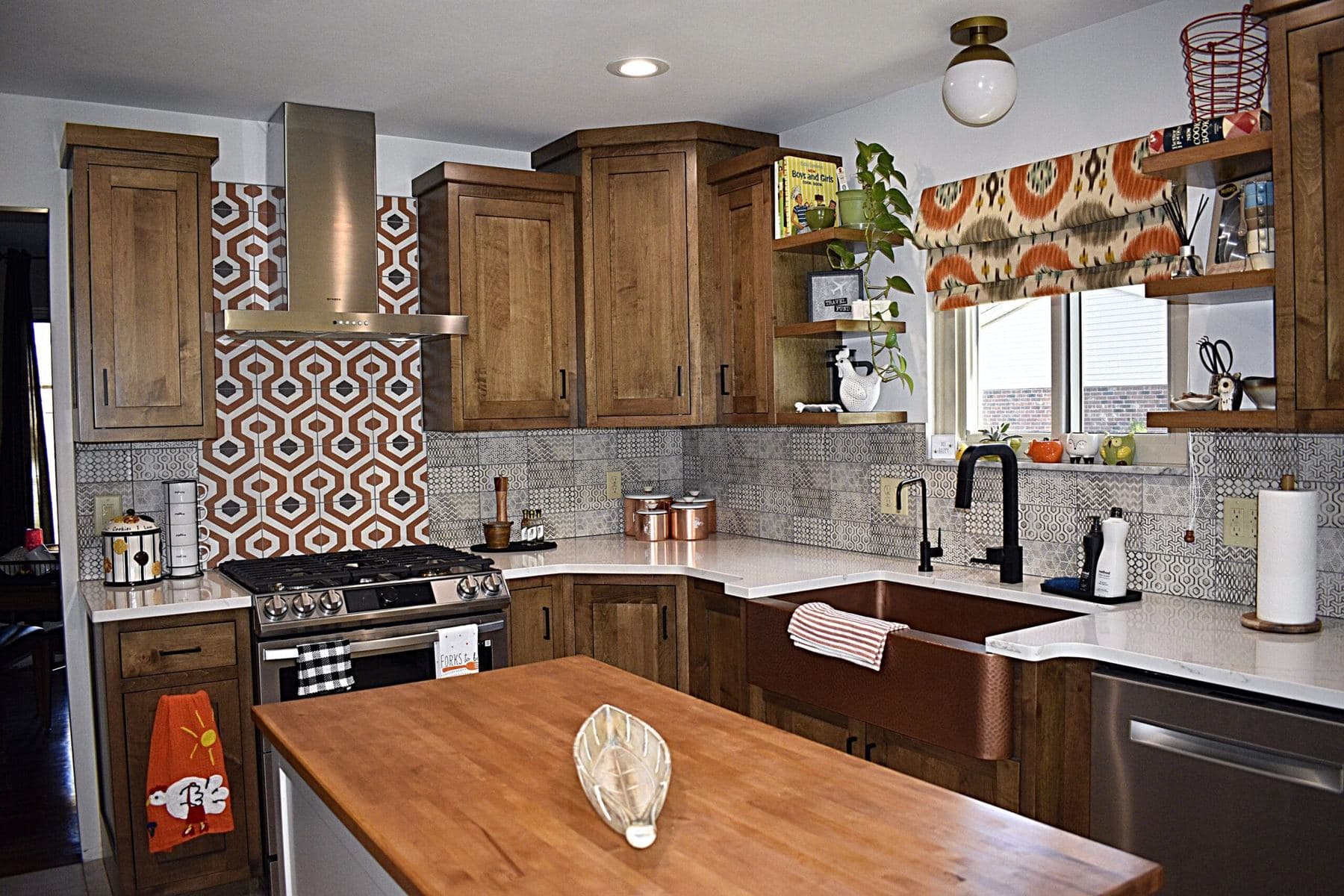 Stained wood kitchen cabinets with a copper farmhouse sink, patterned tile backsplash and butcher block island