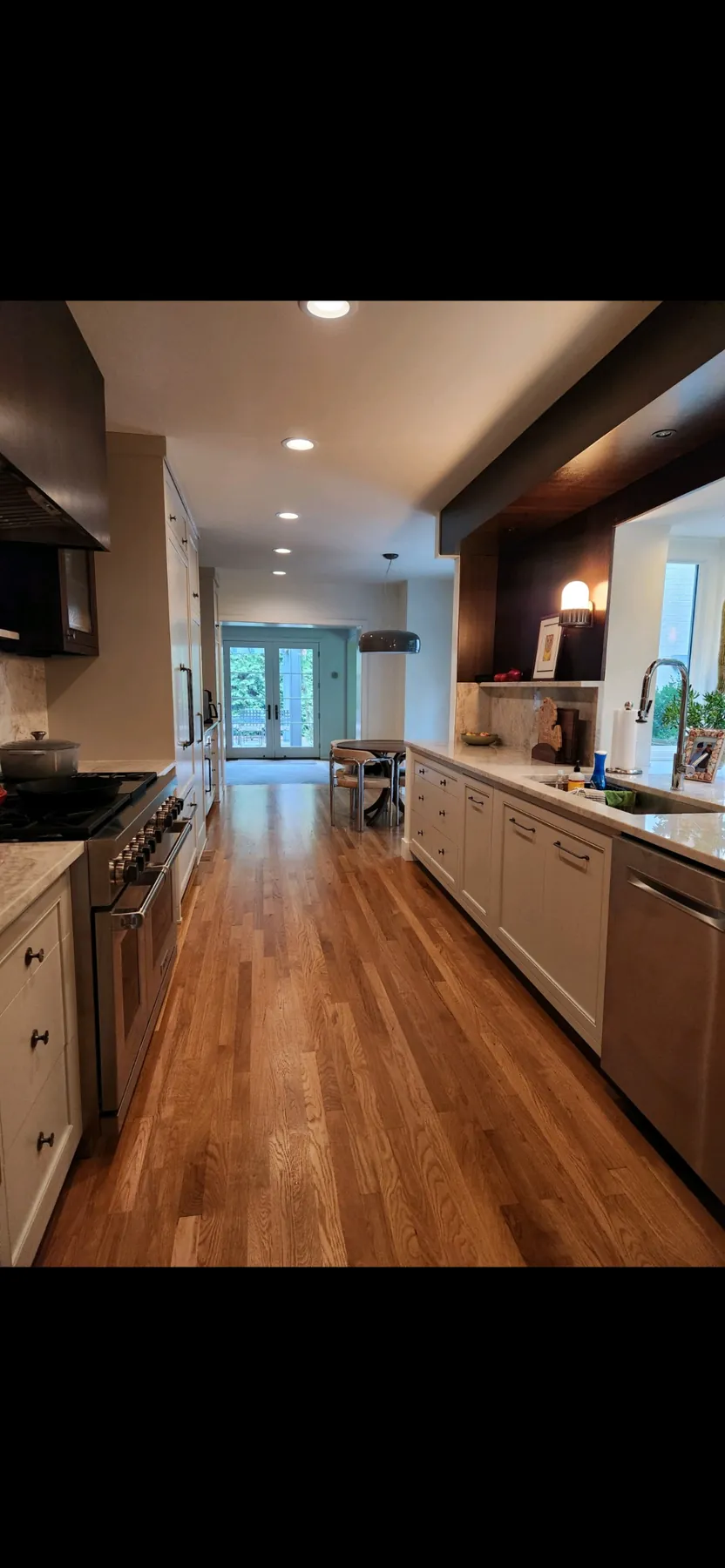 Painted kitchen running the length of the room under a stained wood ceiling