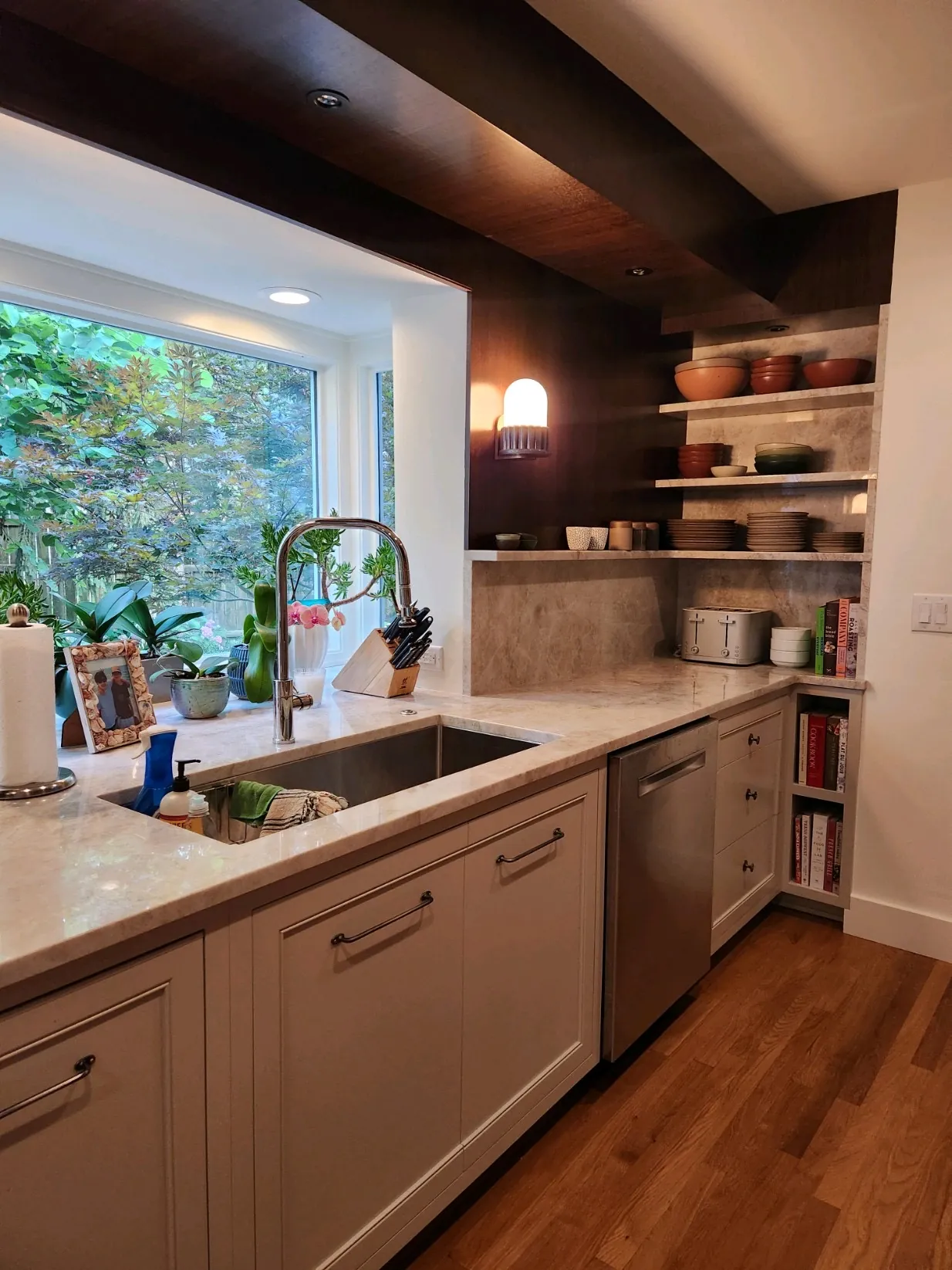 Painted kitchen with marble counters, open shelving and a garden window