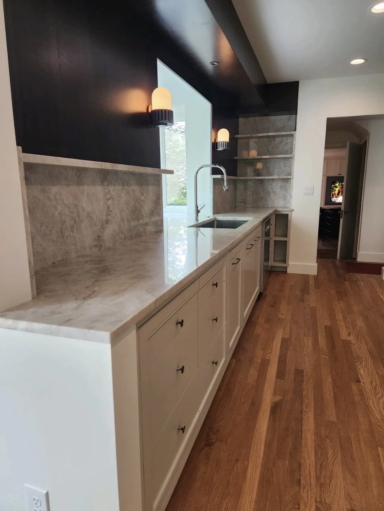 Marble-topped peninsula with painted drawer banks and a dark feature wall