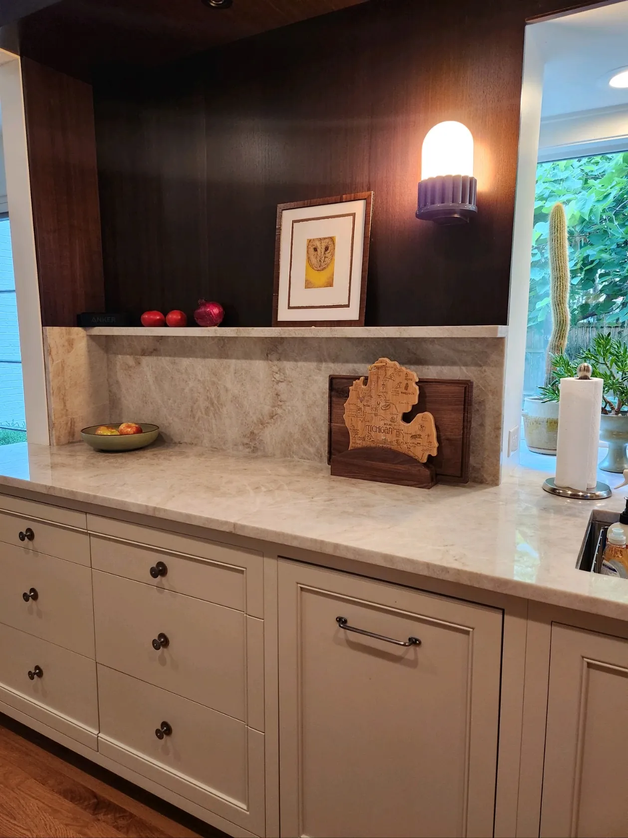Marble backsplash shelf holding art above painted drawers