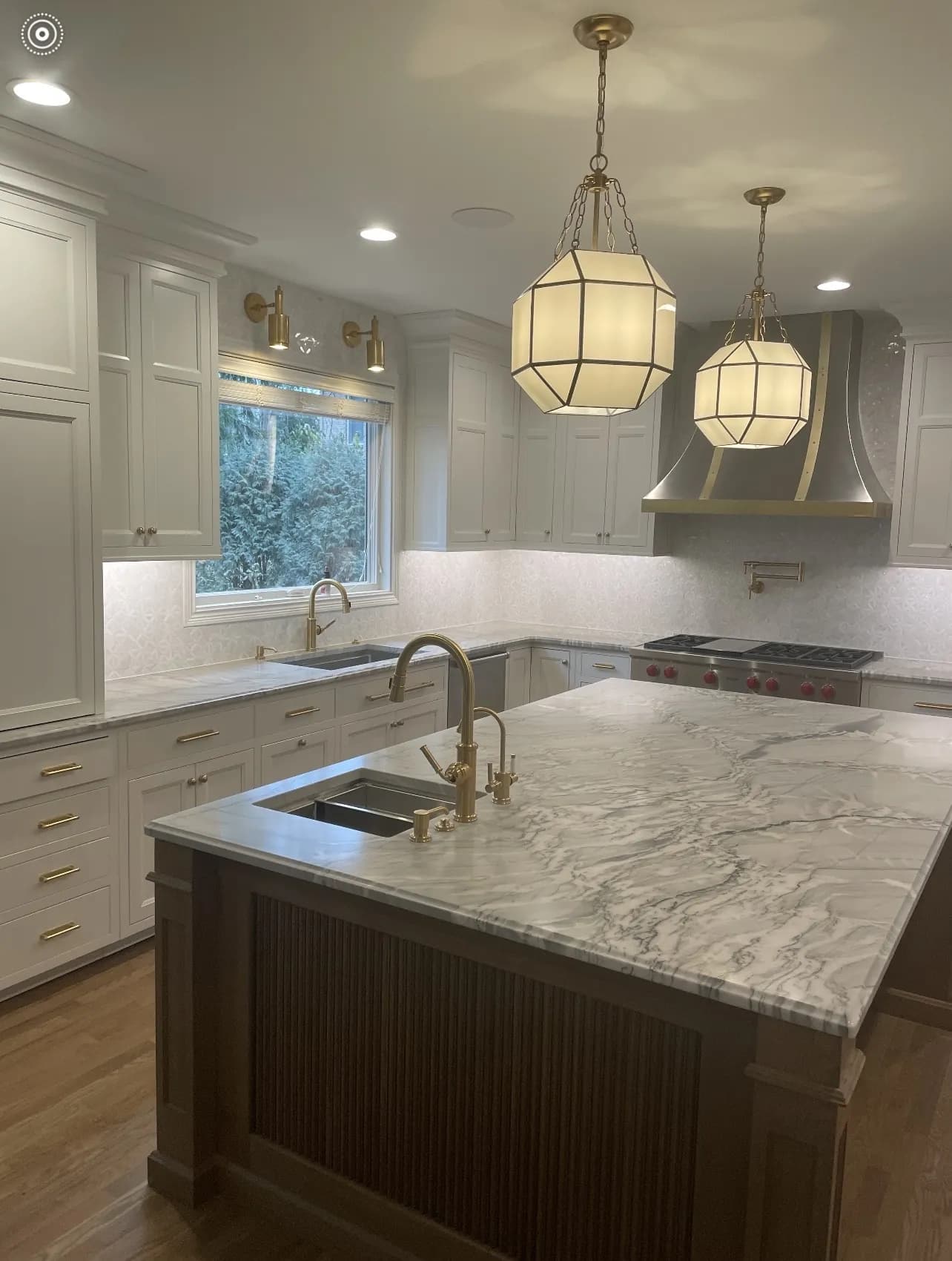 Painted kitchen with a stained island under marble and lantern pendants