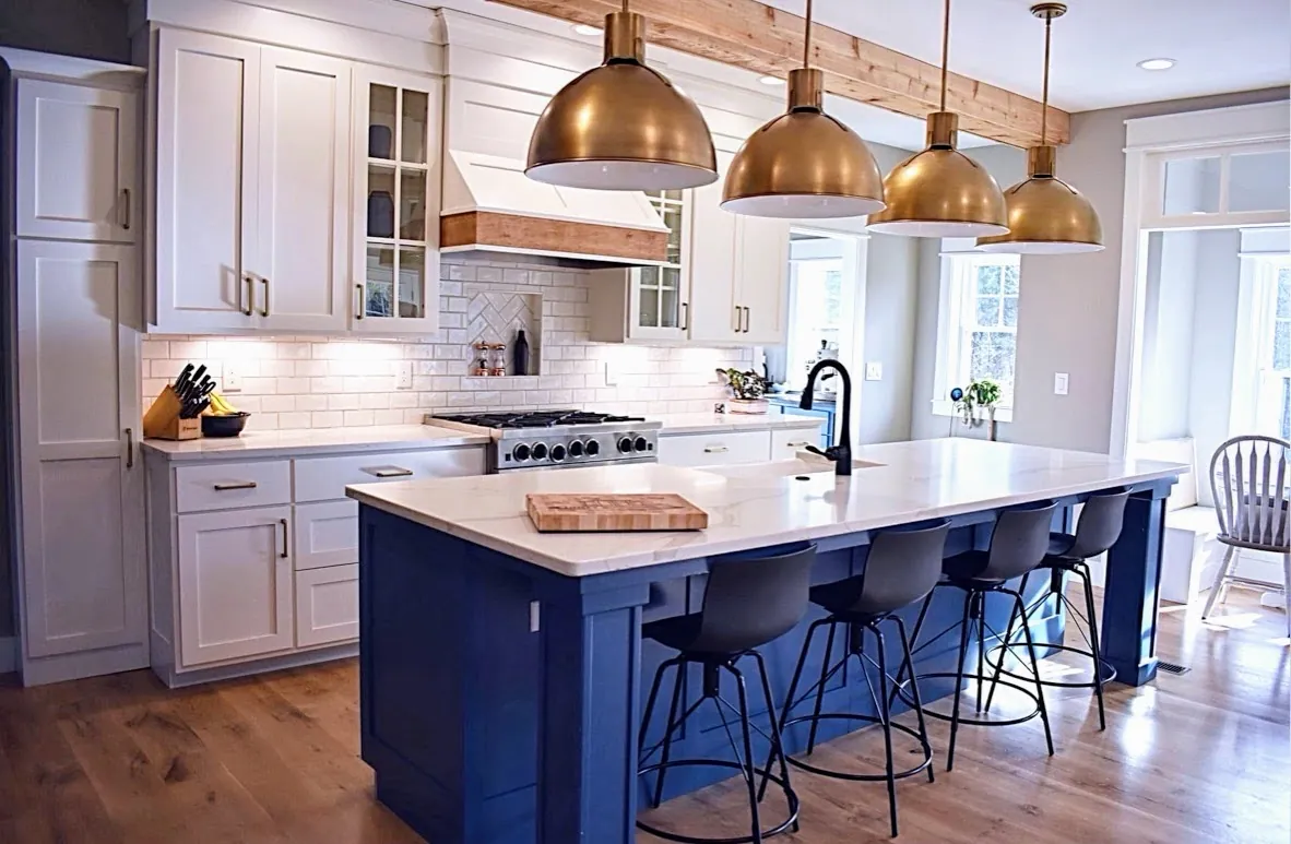 White shaker kitchen with a navy island, brass dome pendants and a beamed ceiling
