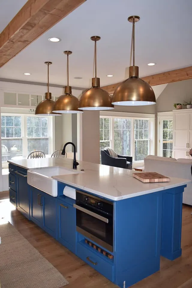 Navy island with a white apron sink and brass dome pendants