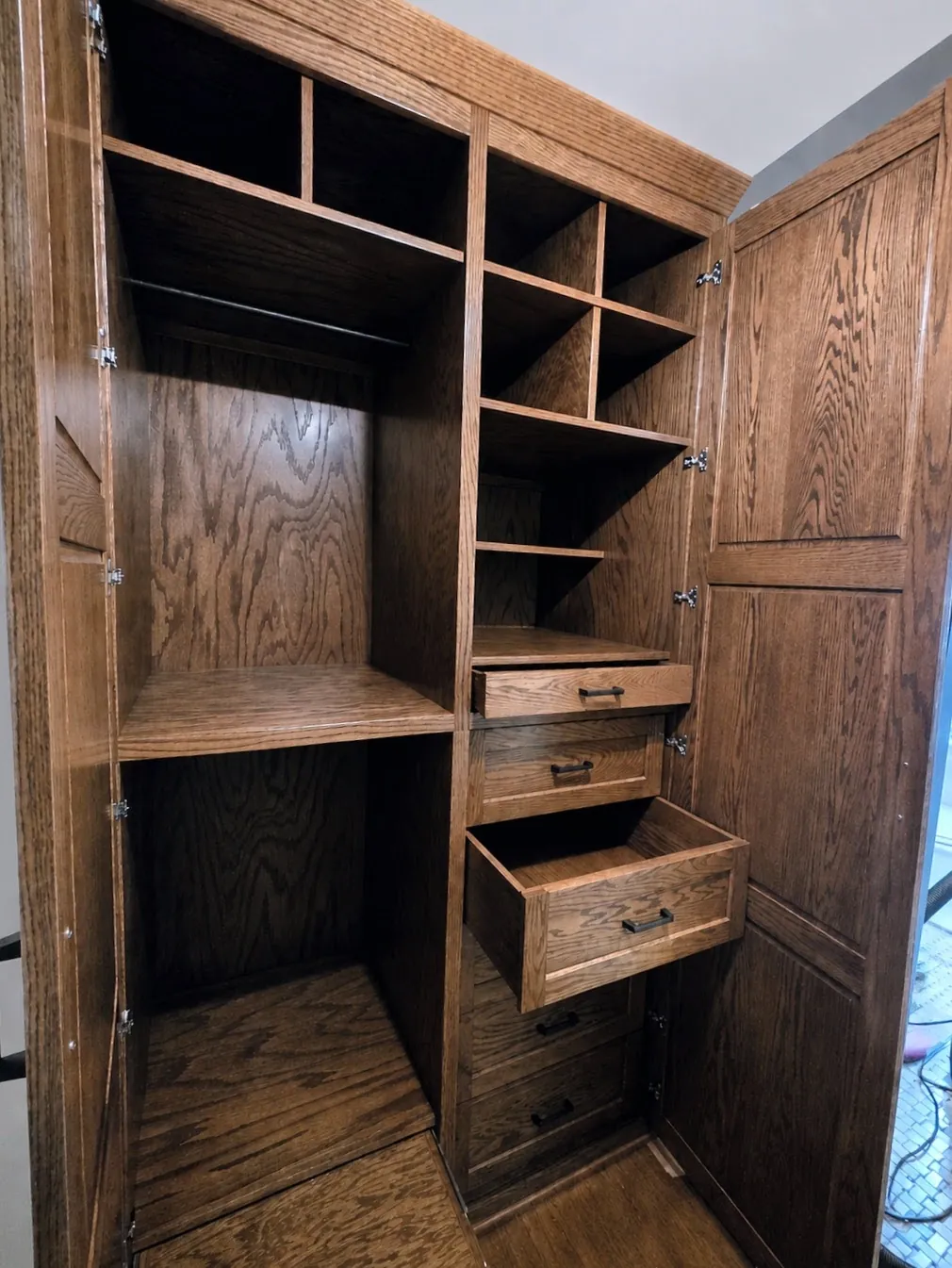 Oak wardrobe with drawers pulled open beside adjustable shelving