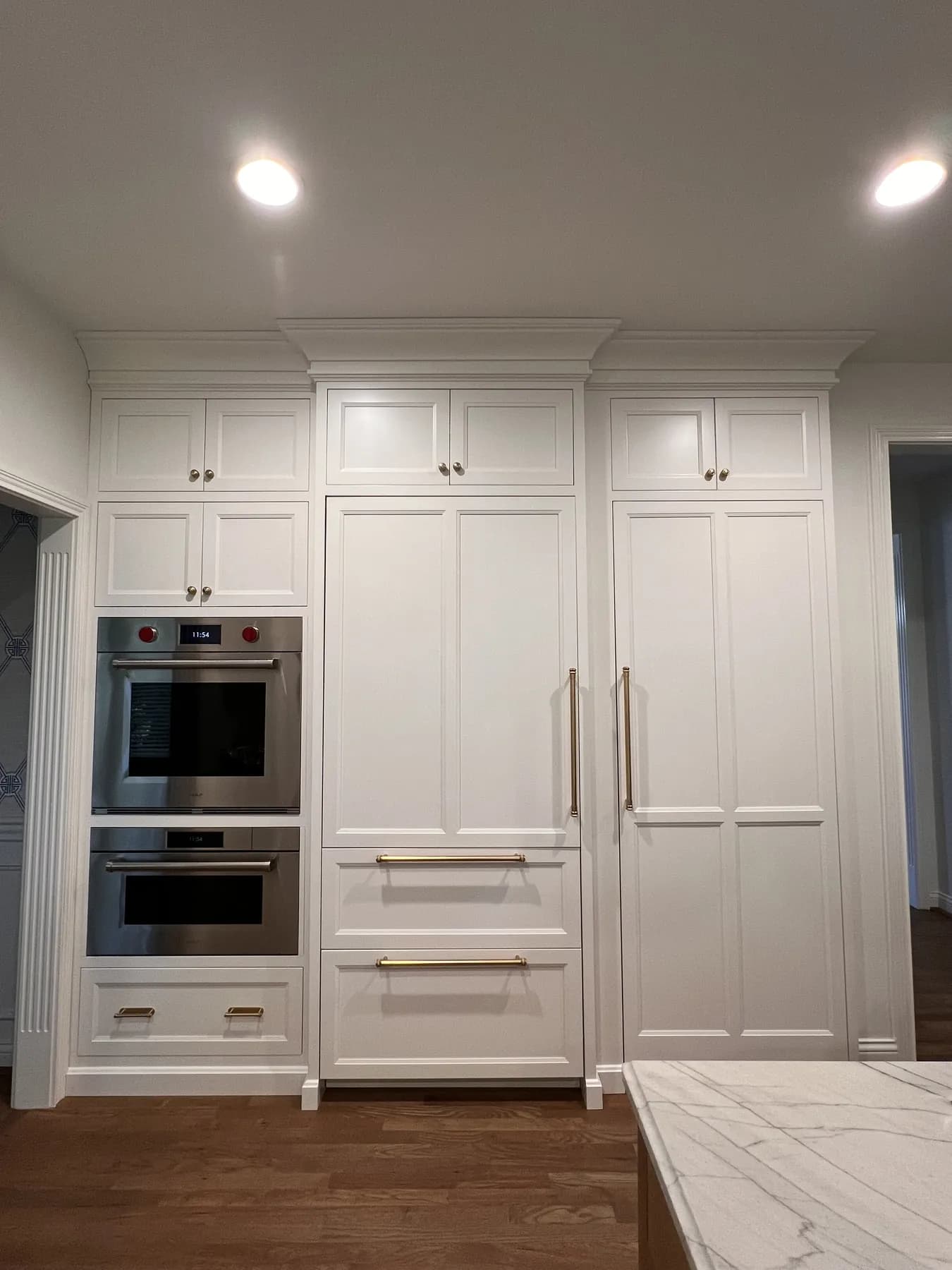 Painted appliance wall with integrated ovens and a panelled refrigerator