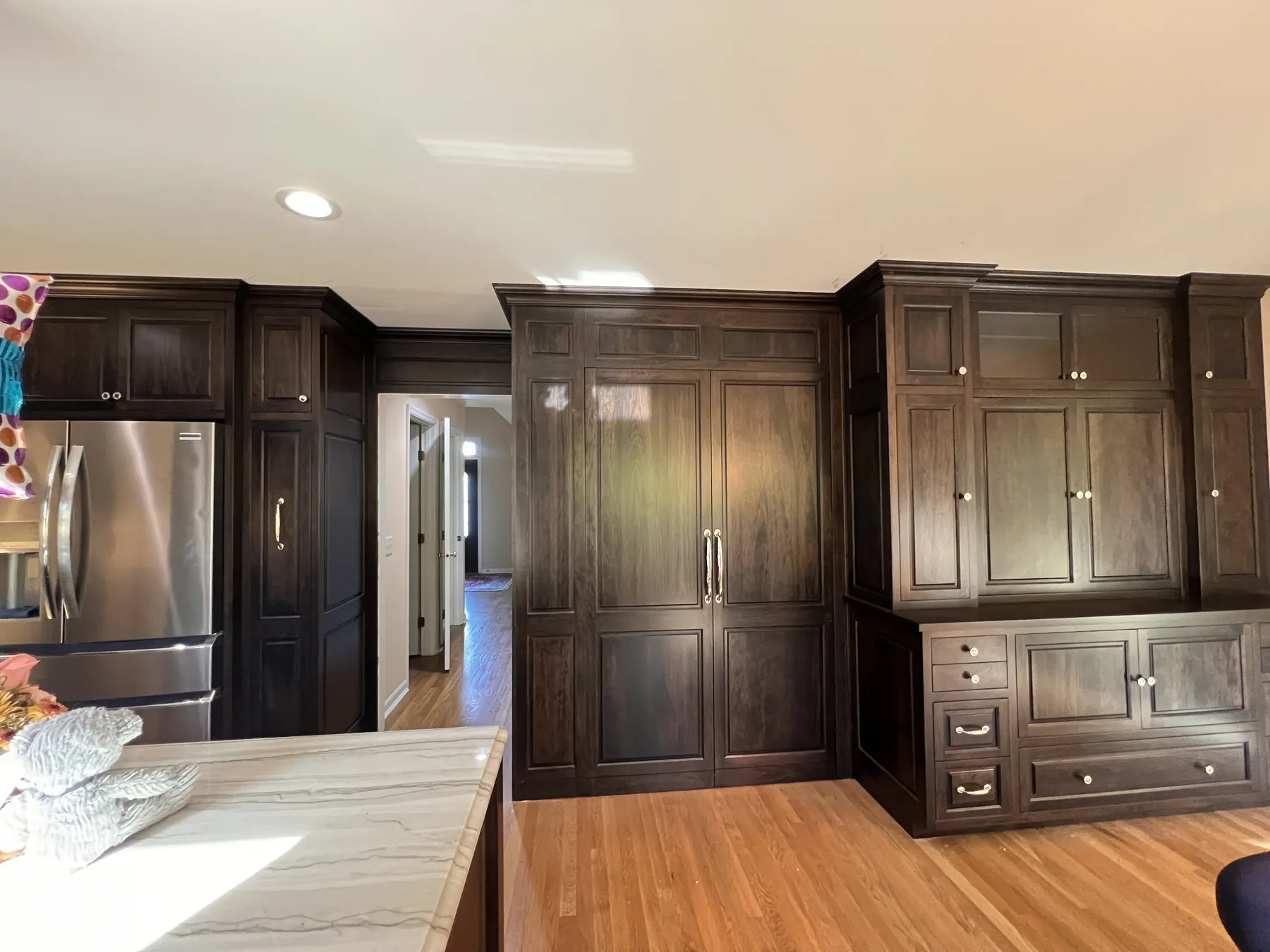 Stained tall cabinets and a marble-topped island in the stained kitchen