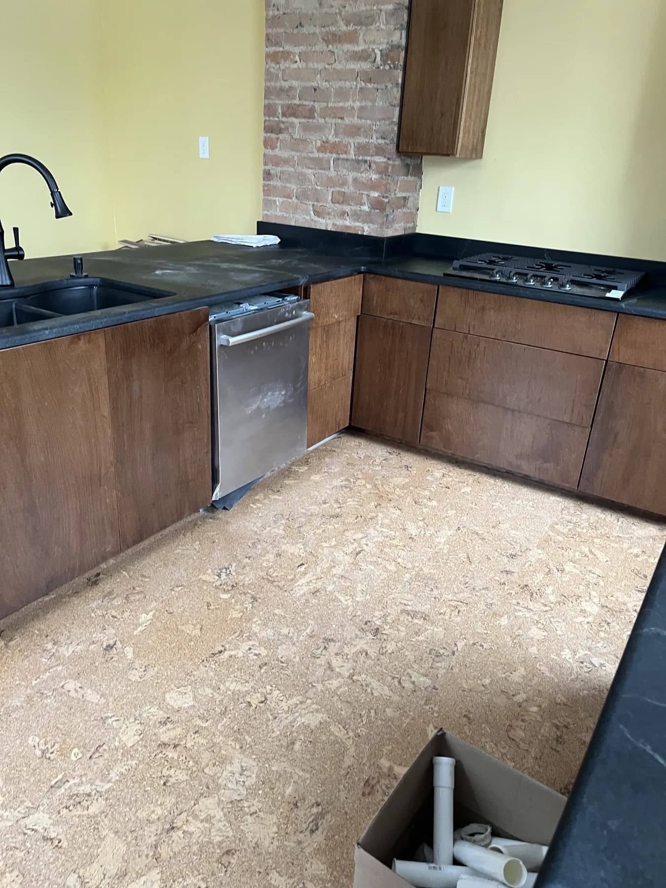 Stained L-shaped kitchen with black stone counters and an integrated dishwasher
