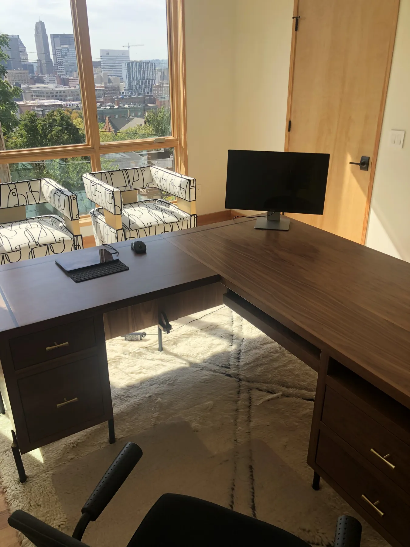 Stained L-shaped desk built into the home office beneath the windows