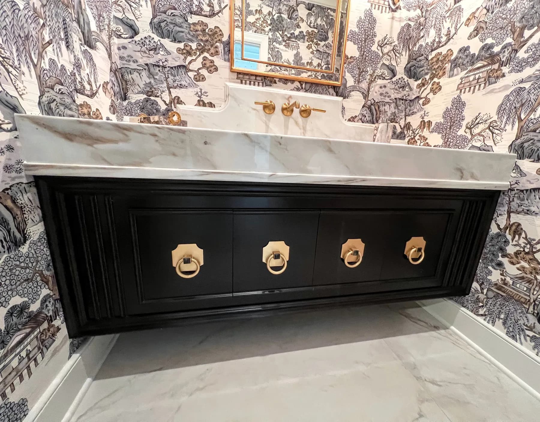 Marble-topped black vanity with four brass ring pulls