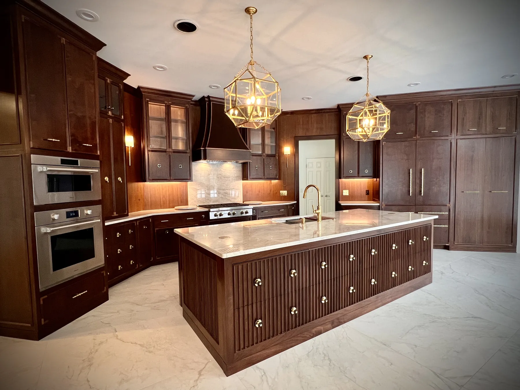 Walnut kitchen with glass-front uppers, a panelled hood and a marble-topped island
