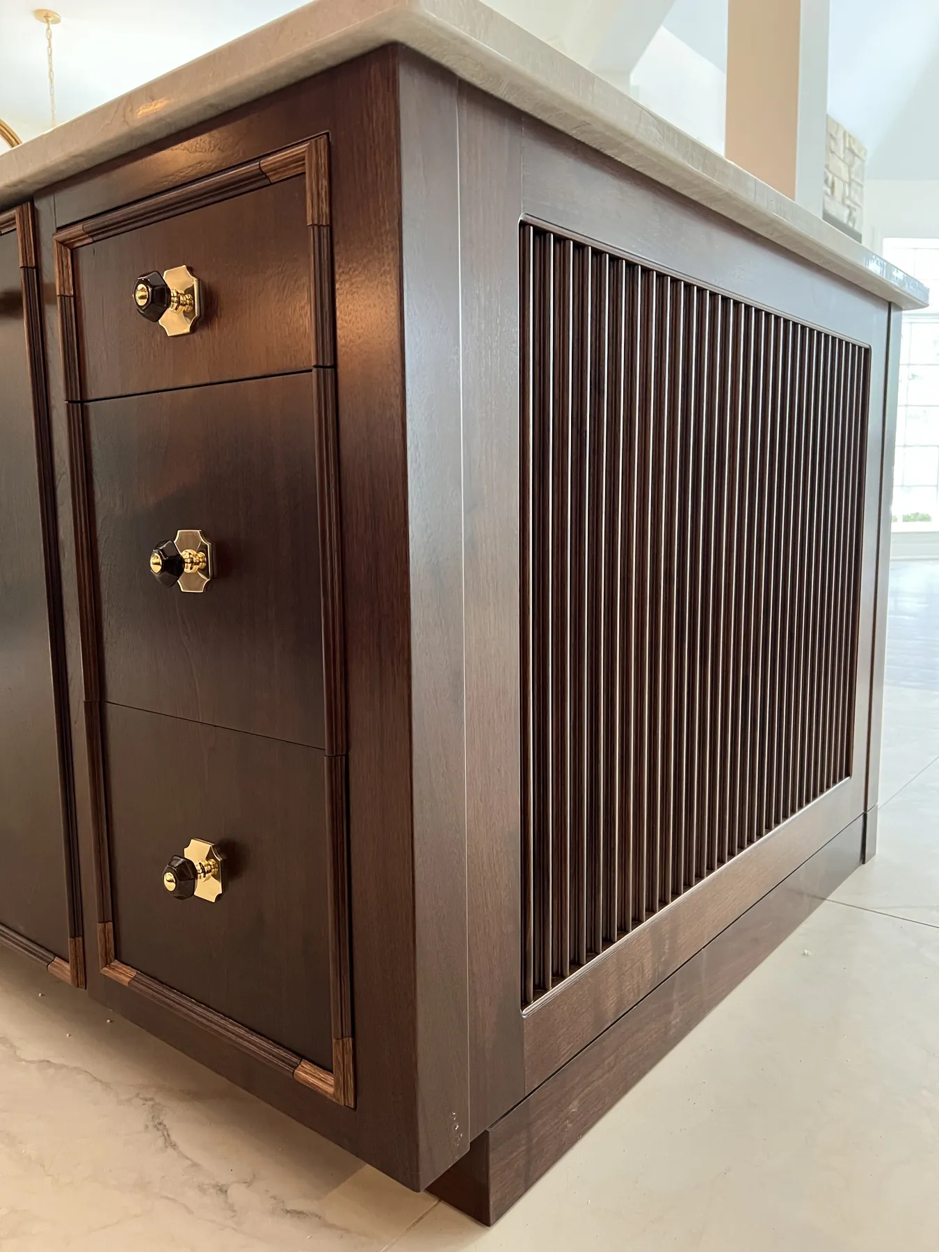 Reeded end panel and brass-knobbed drawers on the walnut island
