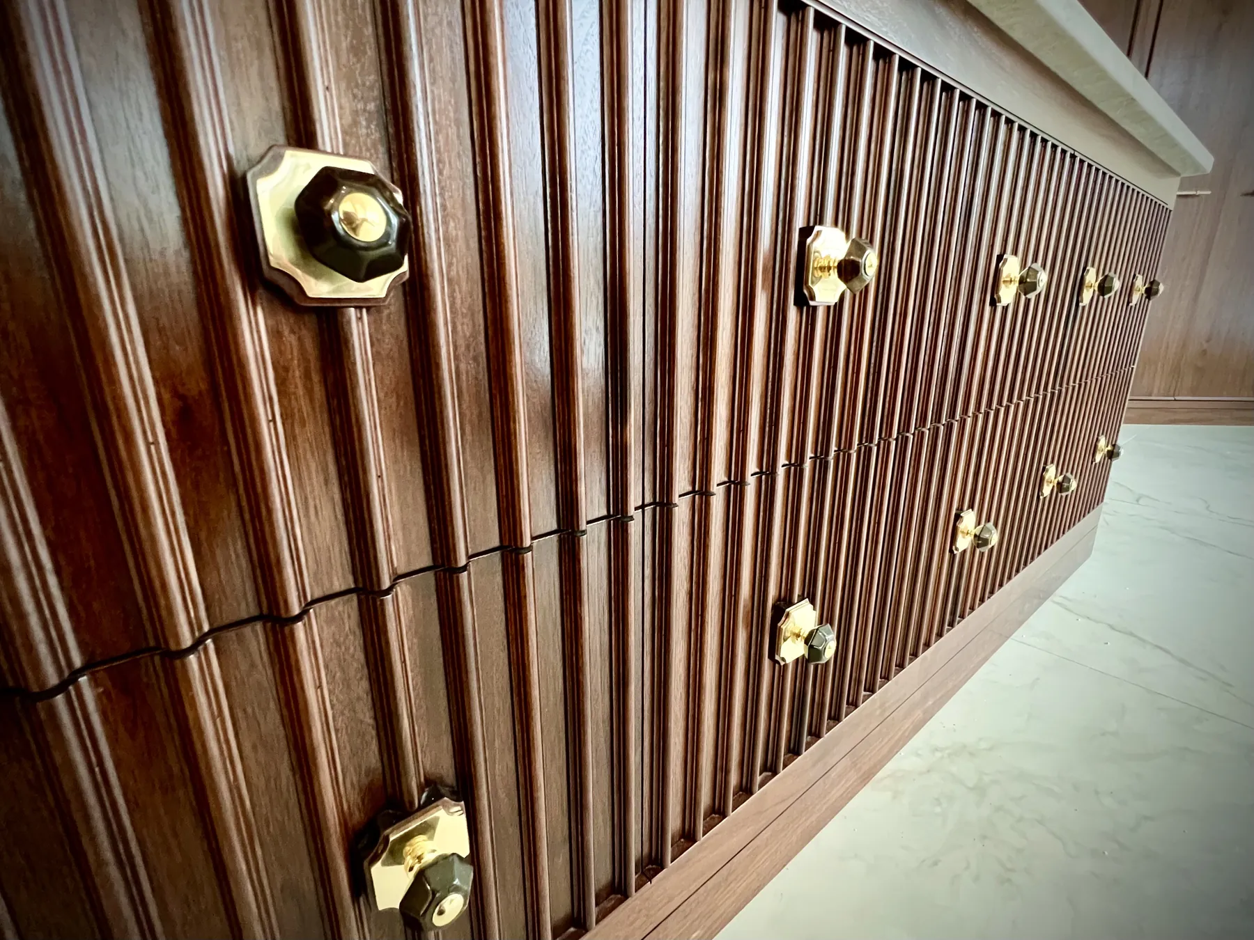 Brass-knobbed reeded drawer fronts seen along the length of the island