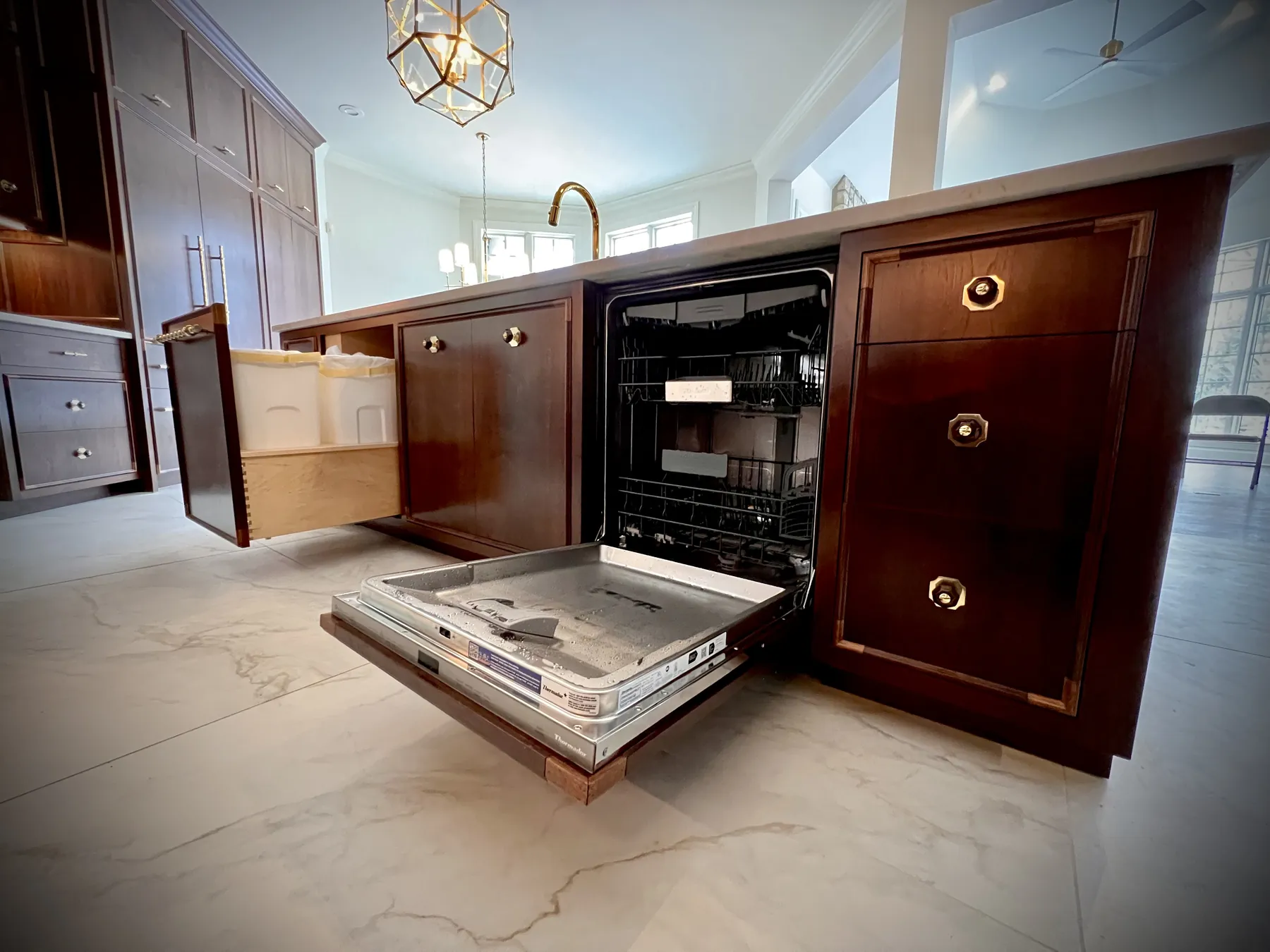 Panelled dishwasher front swung open in the walnut island