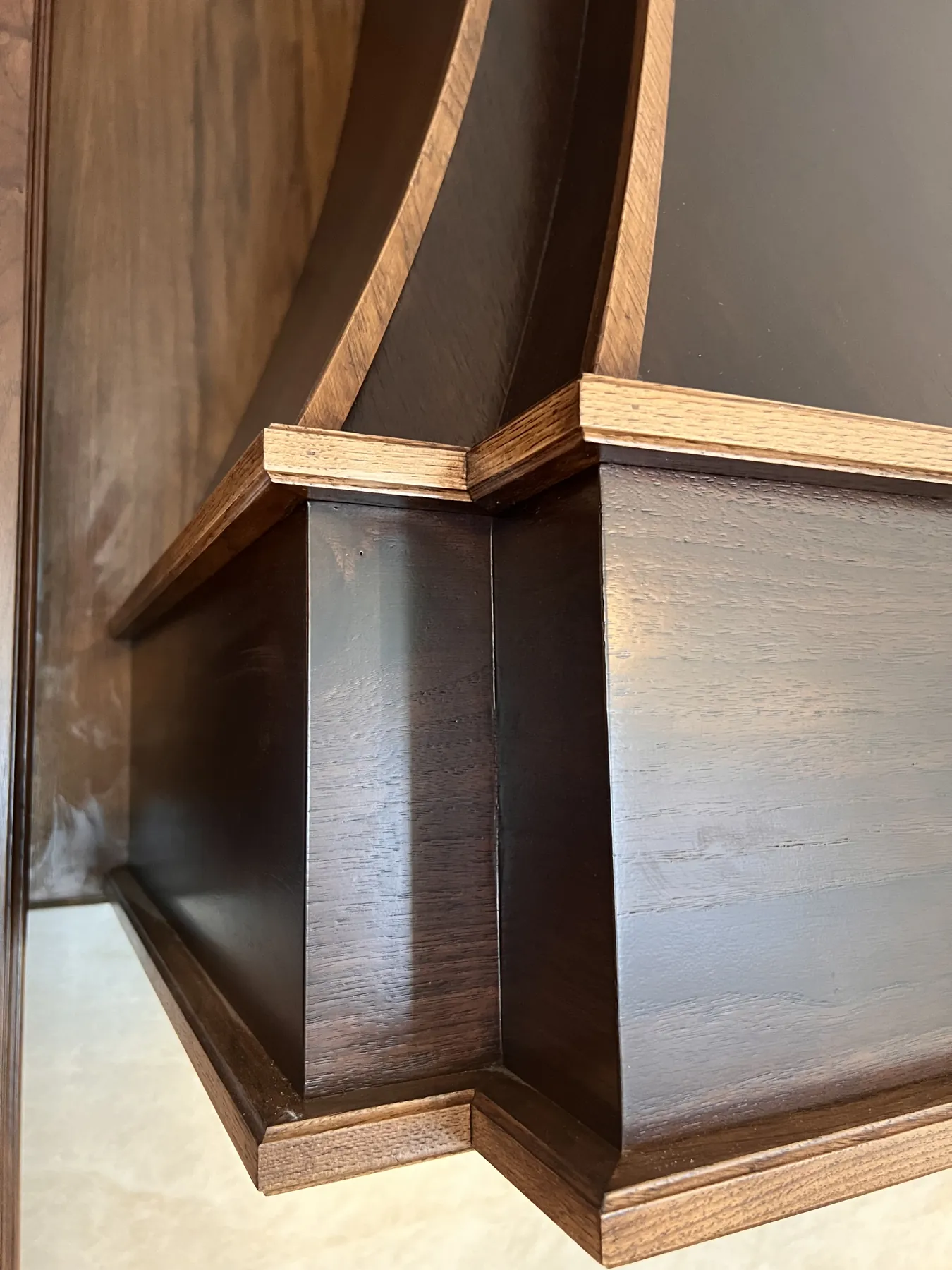 Close view of the curved walnut hood and its mitred corner