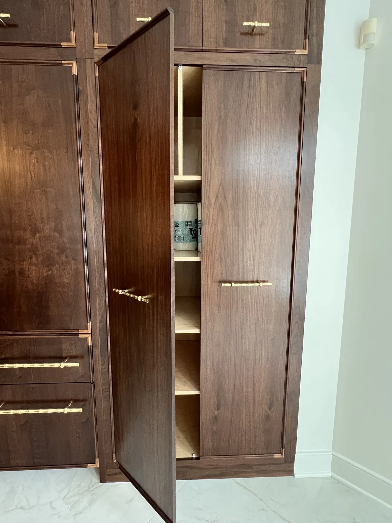 Walnut pantry door swung open on a lit interior shelf