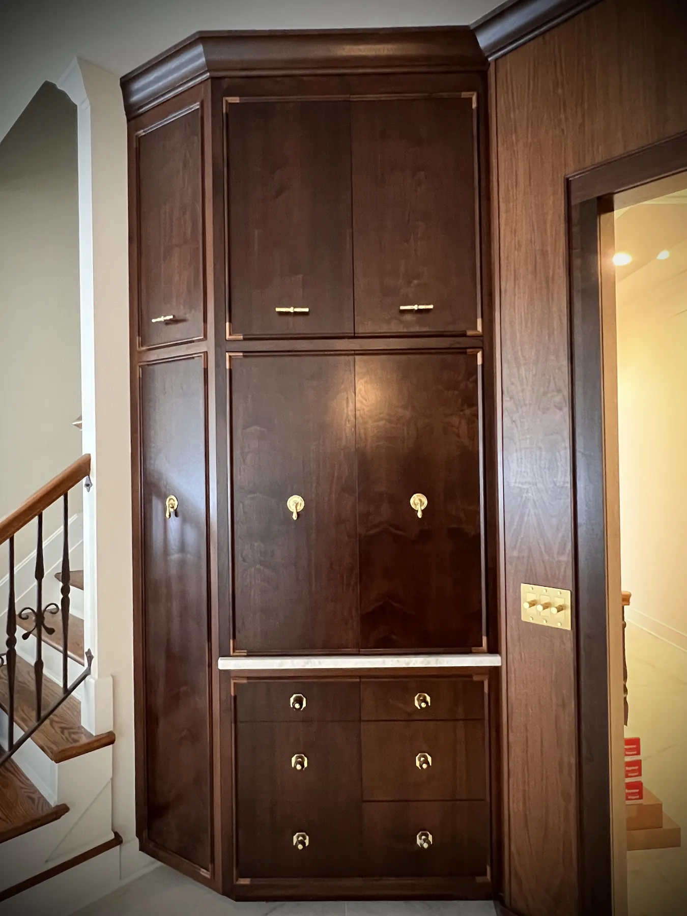 Tall walnut cabinet with inlaid banding beside the stair