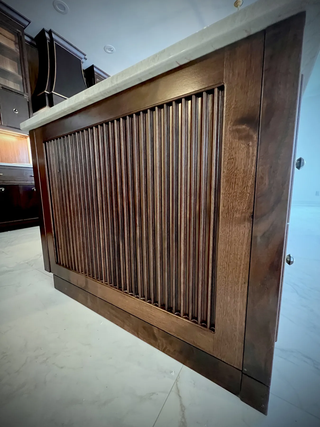 Reeded walnut cabinet end panel meeting a marble counter