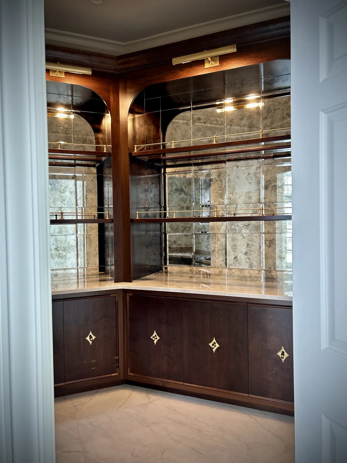 Antiqued mirror bar with walnut cabinetry and brass gallery rails