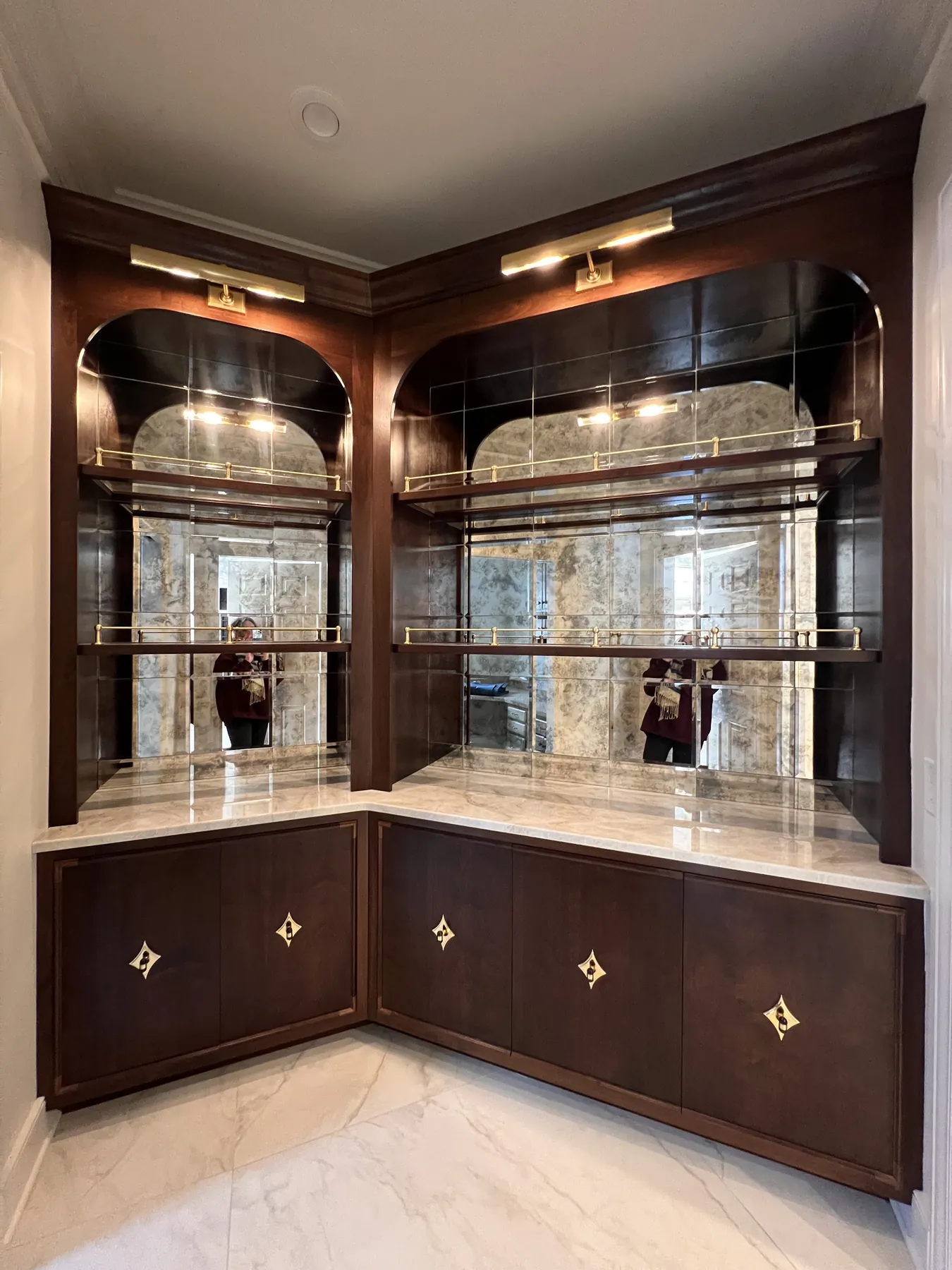 Corner bar with arched antiqued mirror panels above inlaid walnut doors