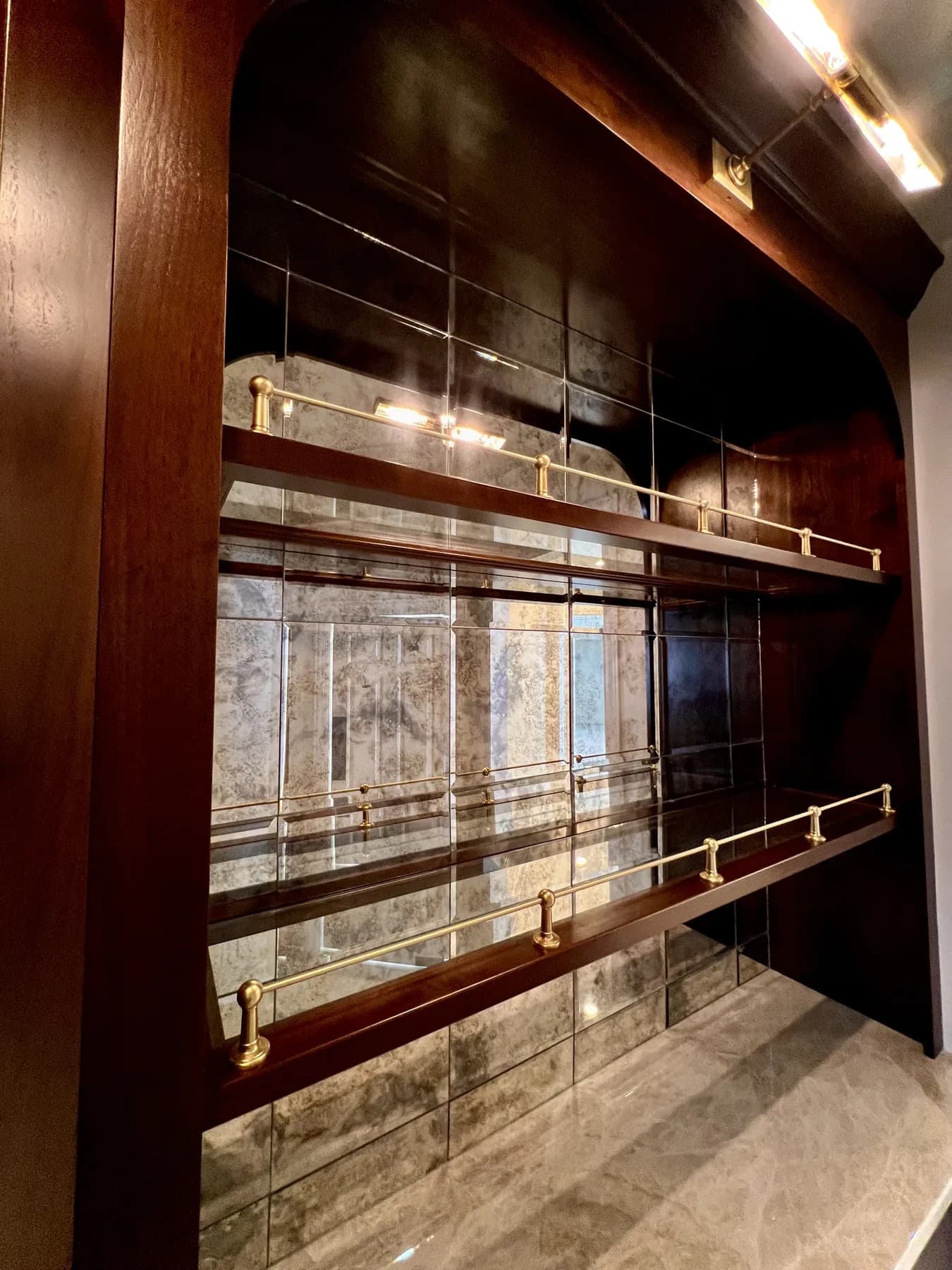 Brass gallery rails across the antiqued mirror of the bar