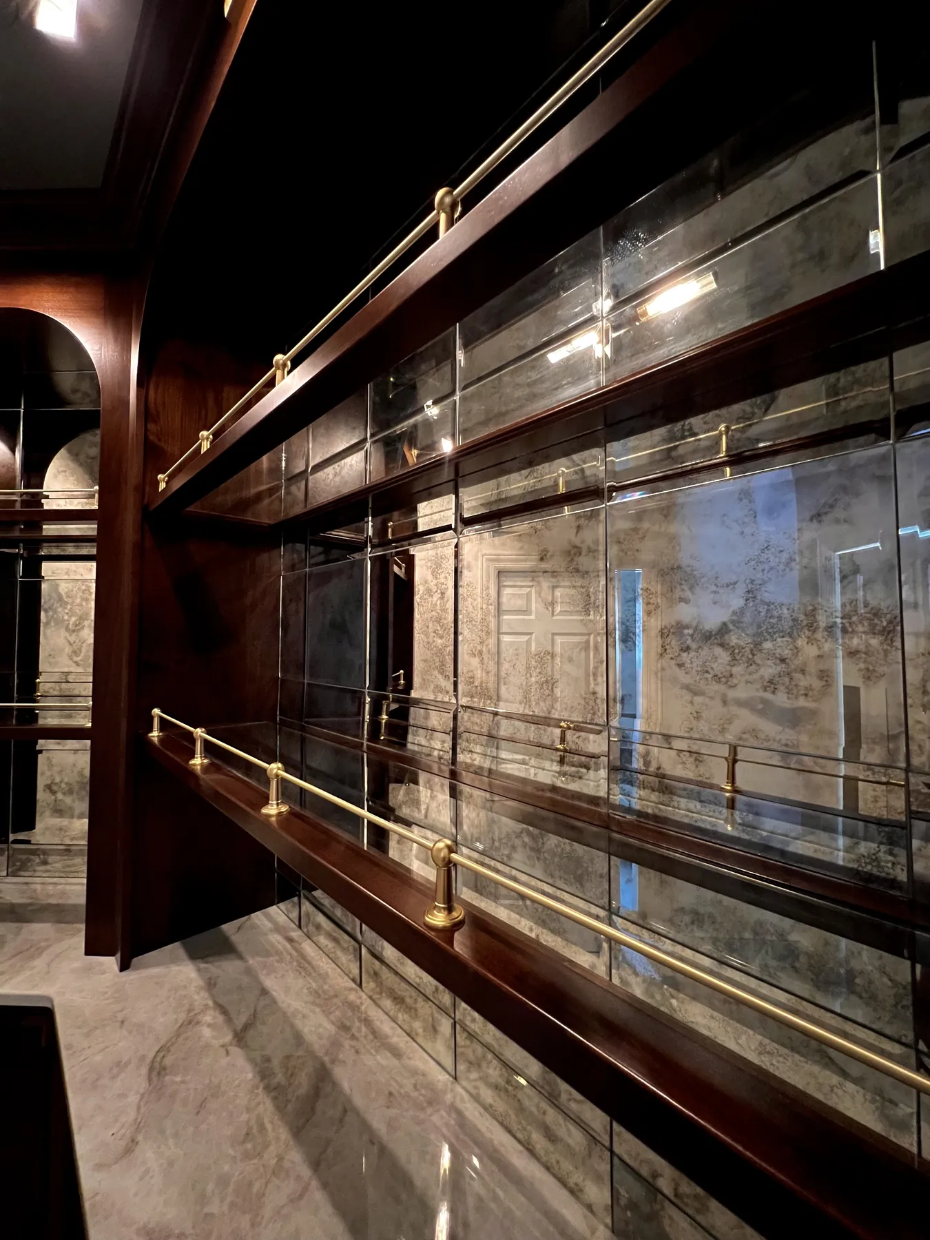 Brass rails running the length of the antiqued mirror bar