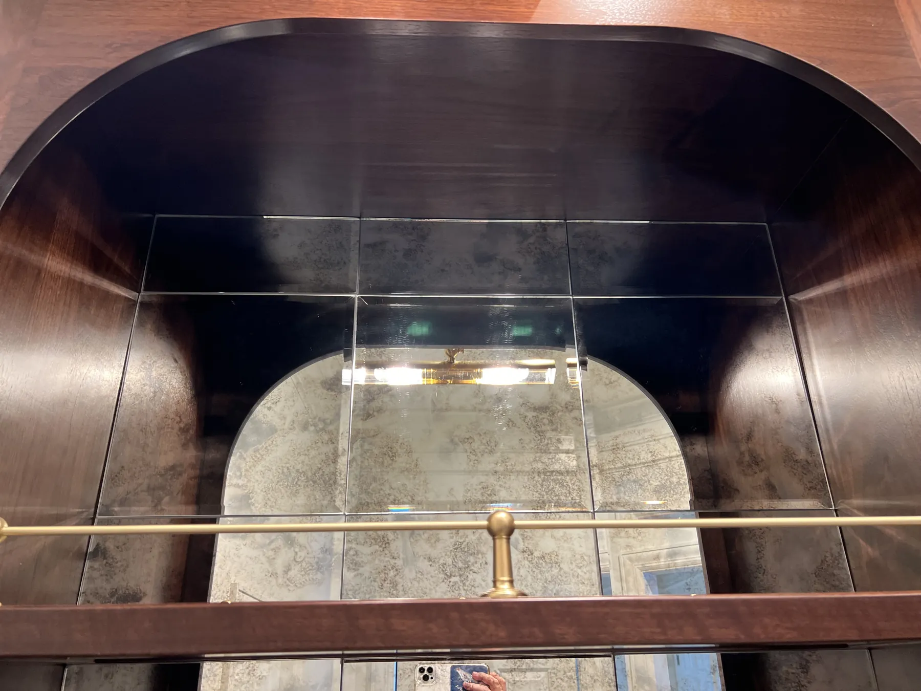 Lit arch of the mirrored bar with a brass rail