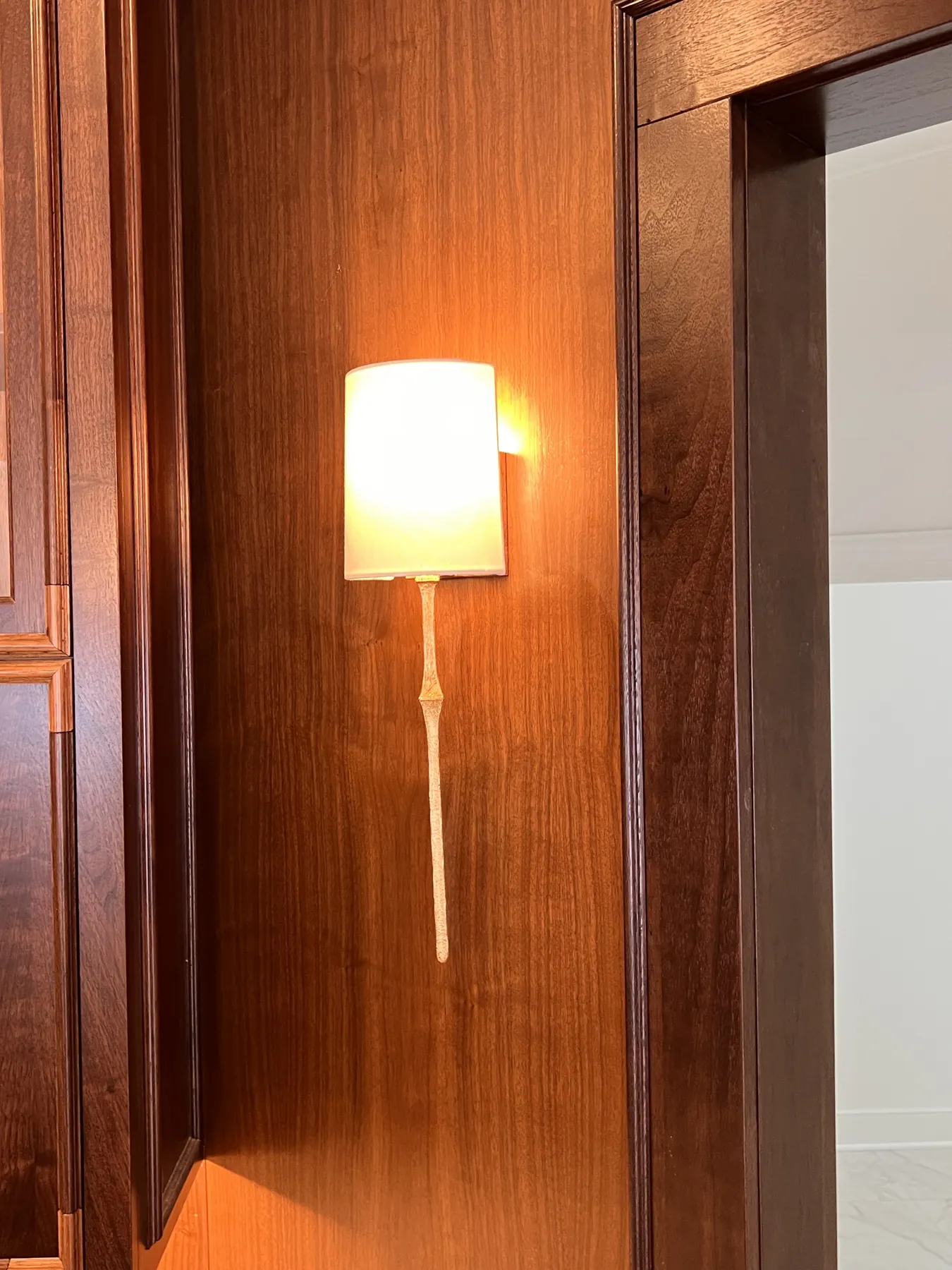 Brass sconce mounted on a stained walnut panel