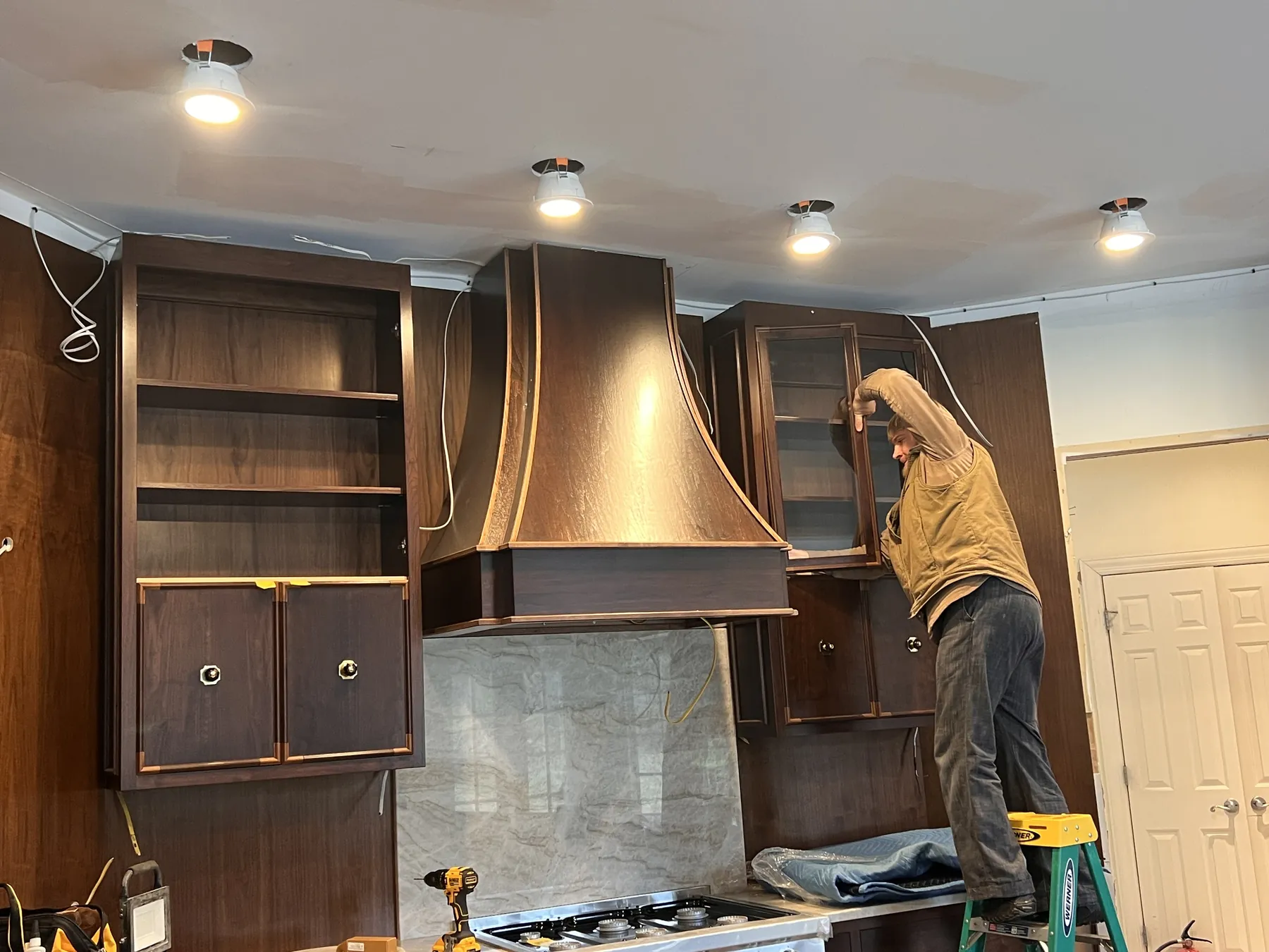 Fitting the curved walnut hood above the range during install