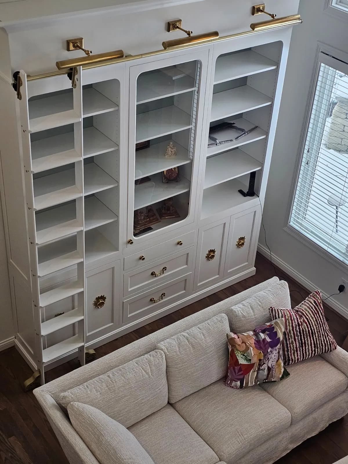 Painted bookcase wall with a rolling ladder seen from the sofa