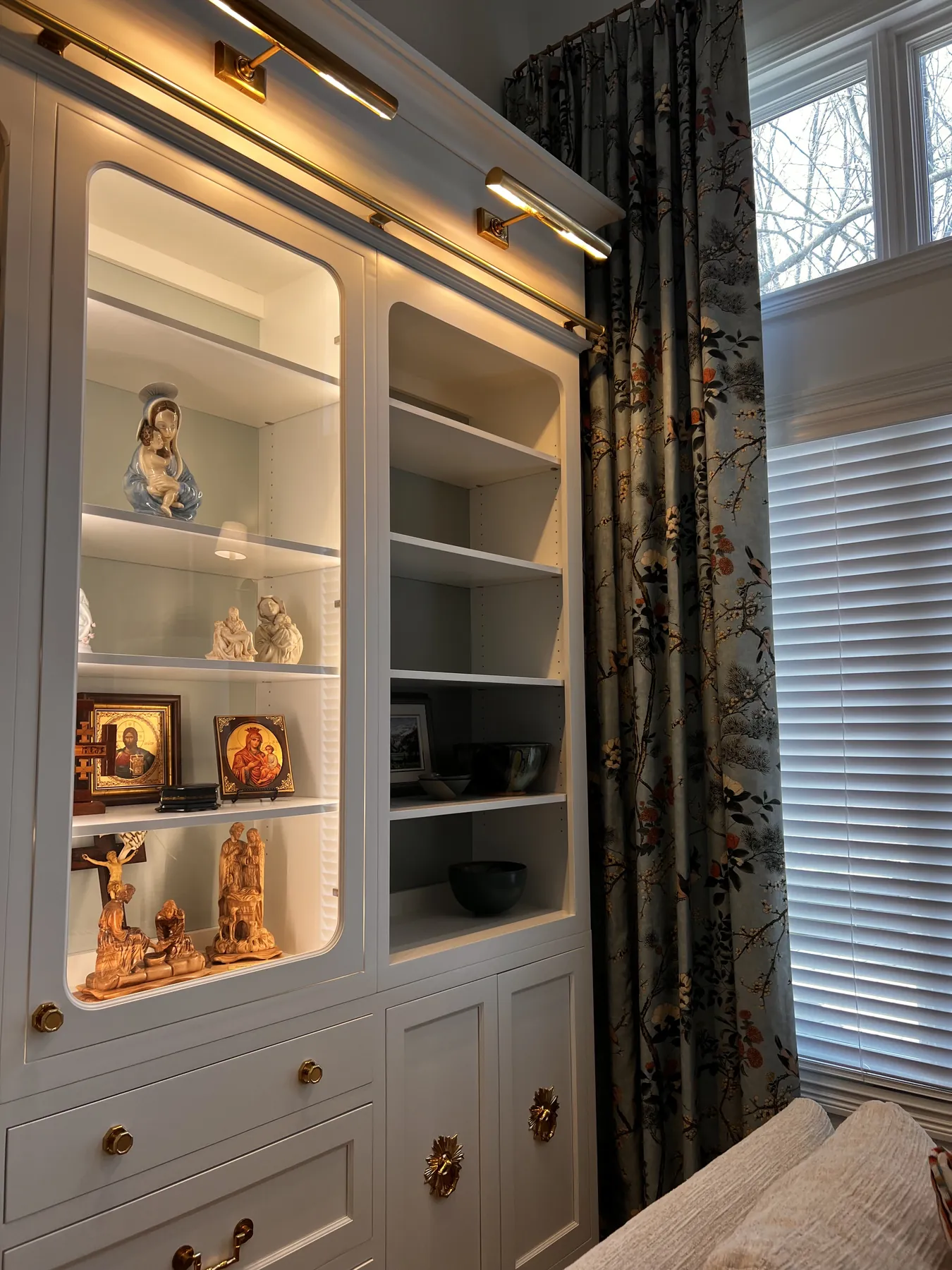 Painted library shelving lit by brass picture lights
