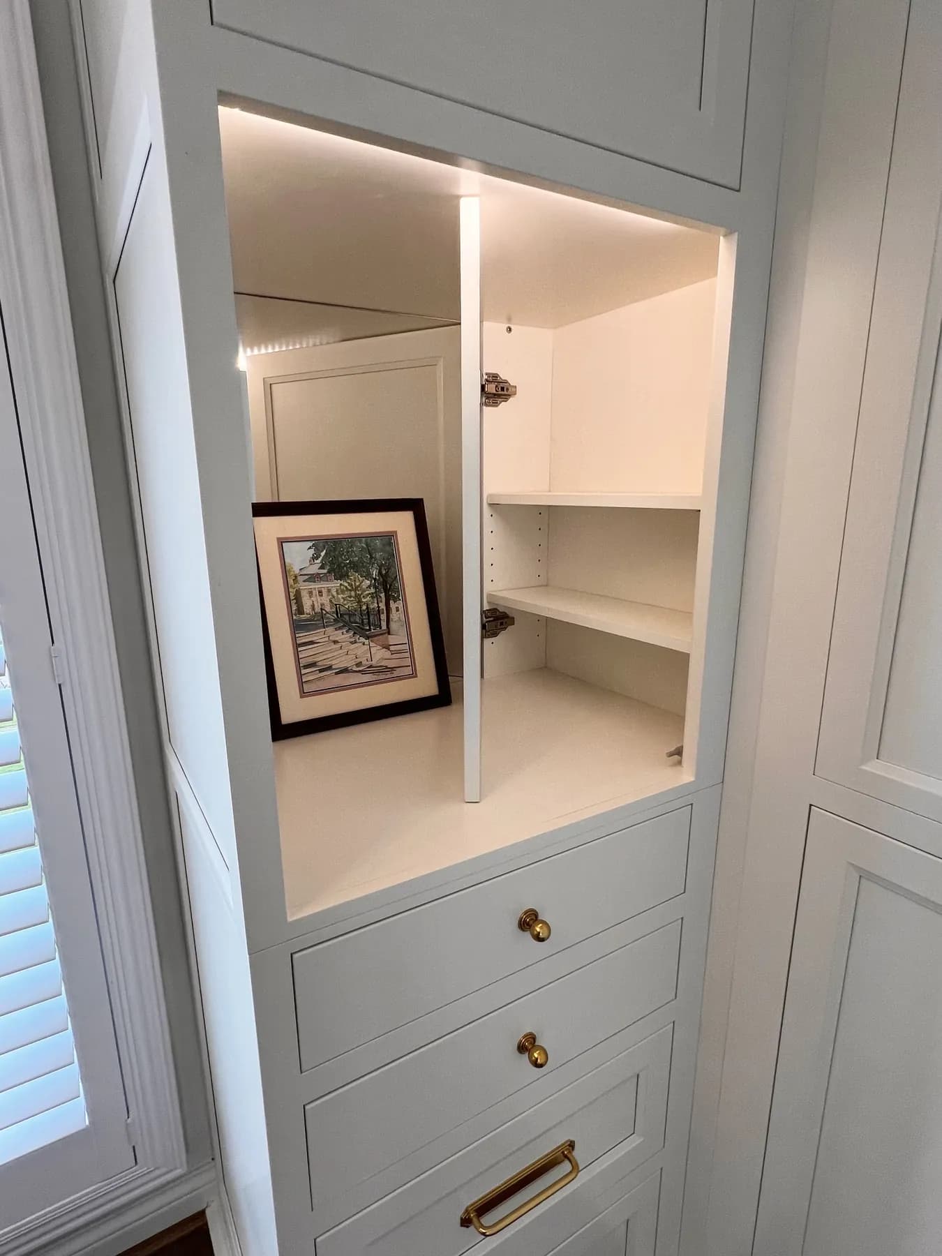 Painted closet cabinetry with open shelving and framed art