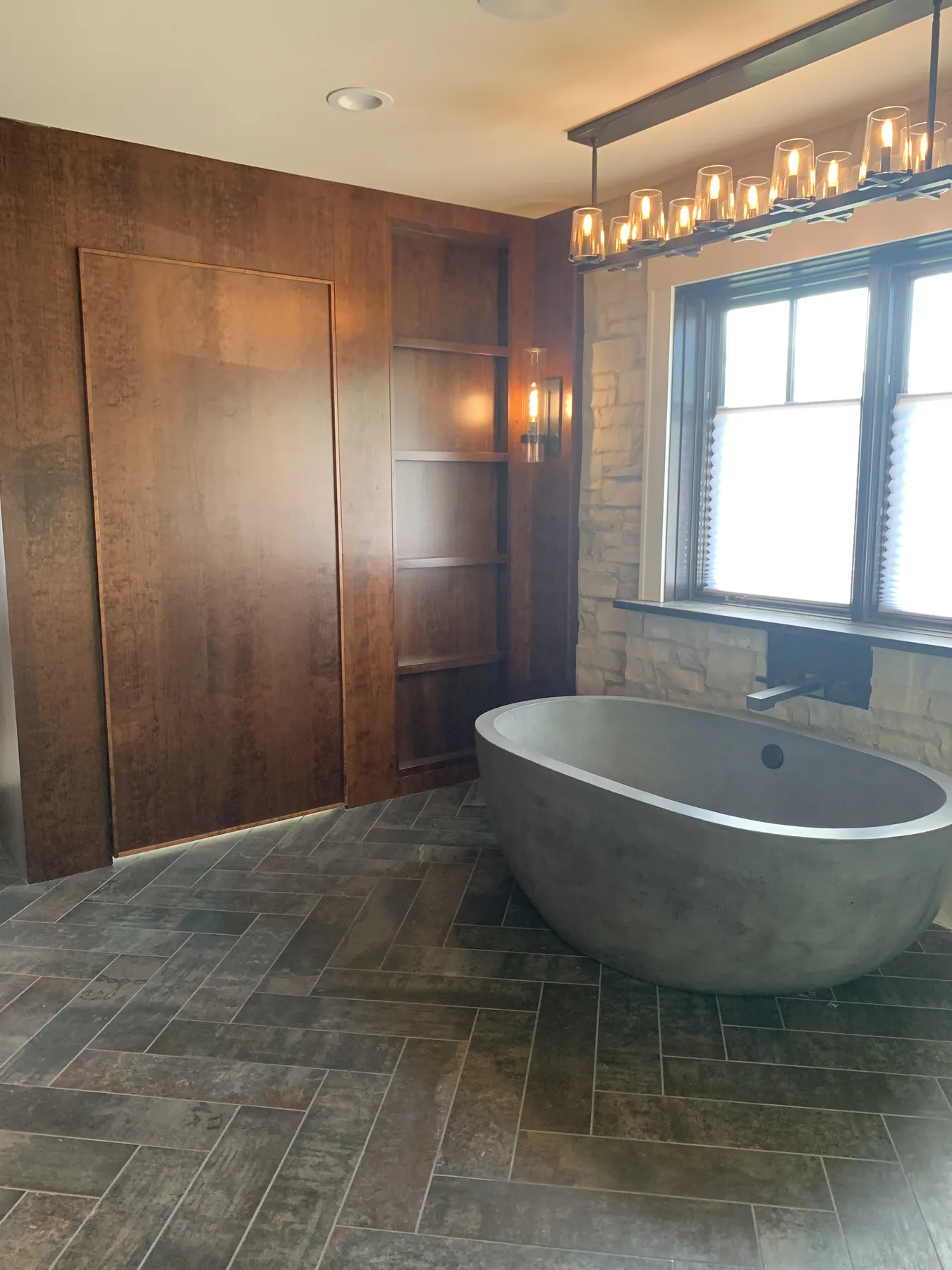 Stained panelled walls around a concrete soaking tub on slate