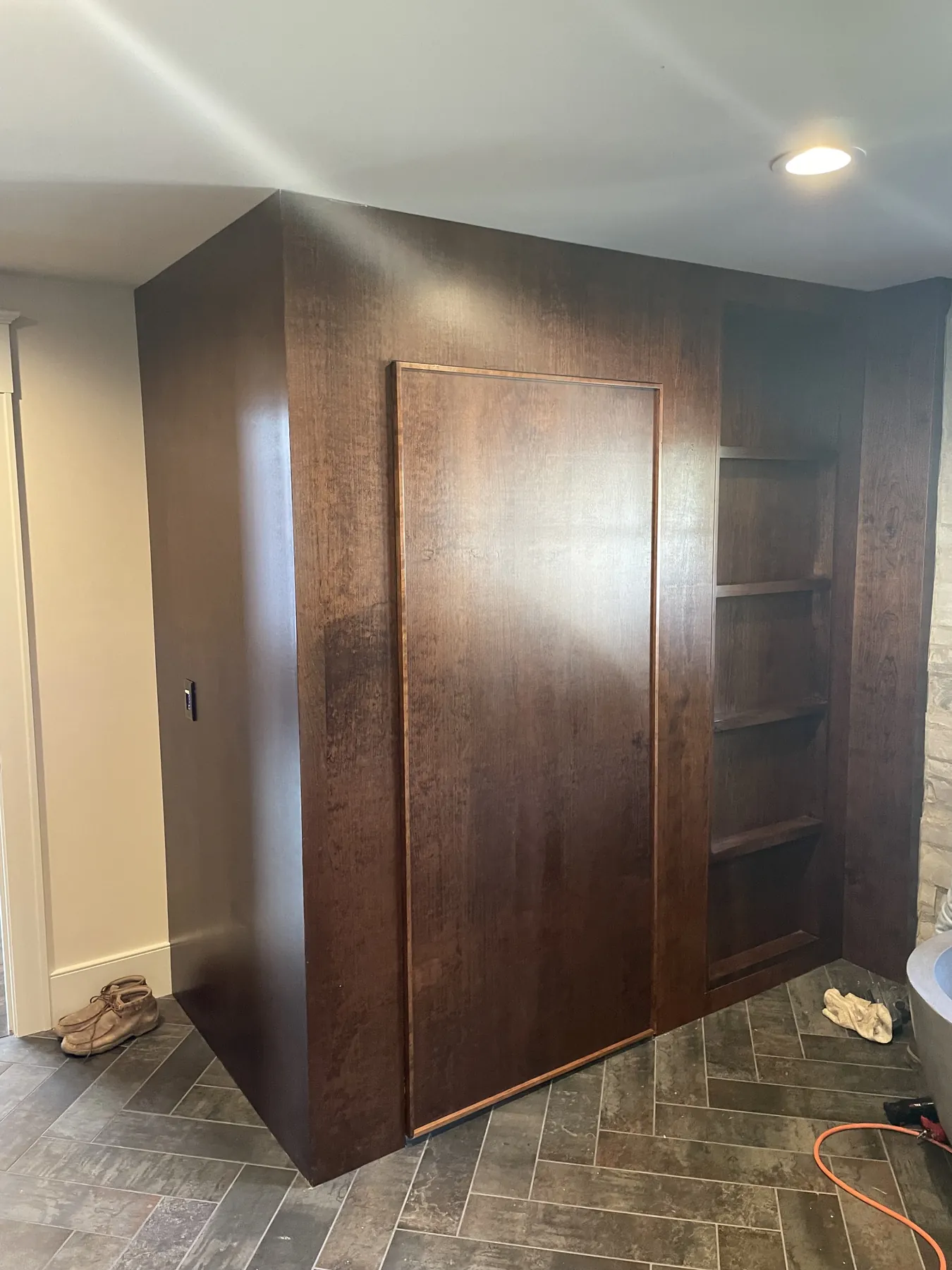 Concealed door set flush into the stained panelling beside open shelves